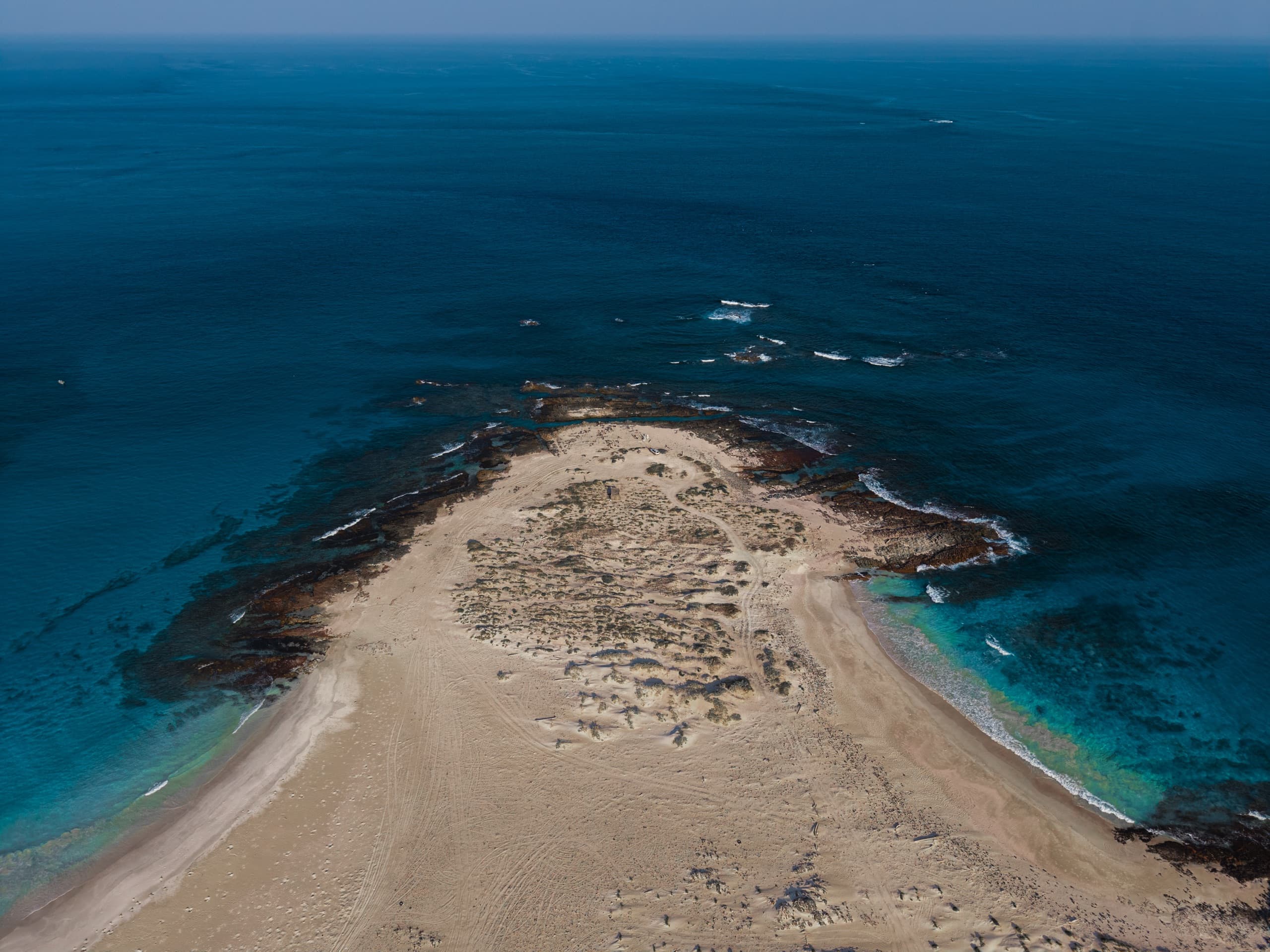 A pale sand cape ringed by reef and open ocean